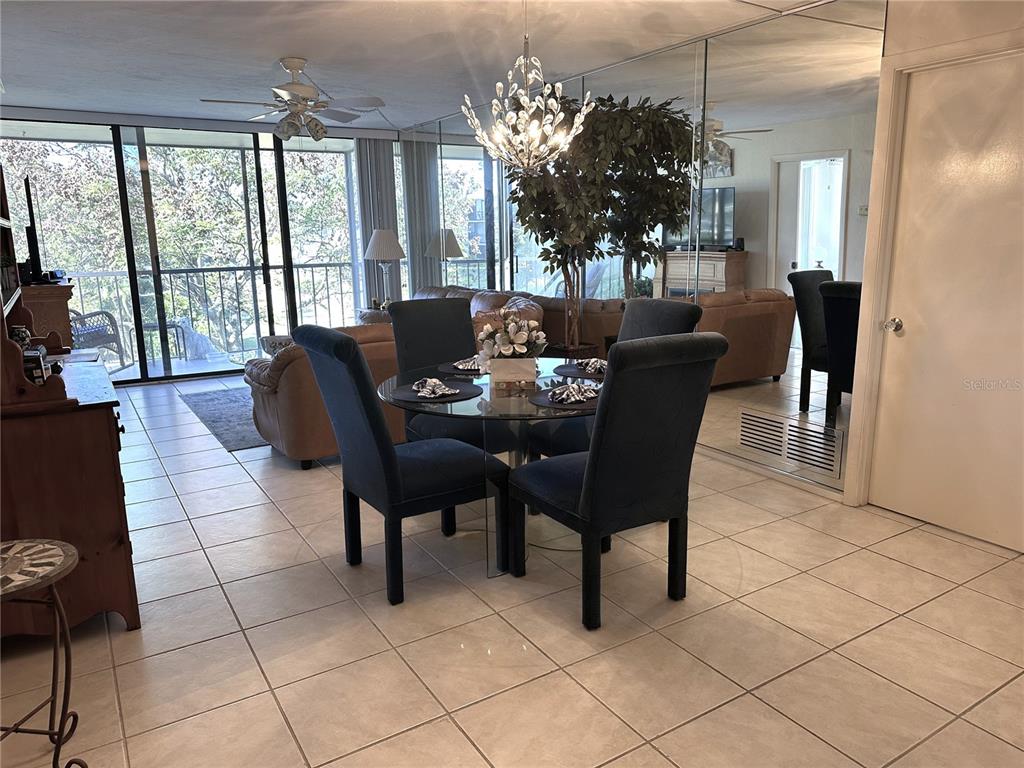 A dining area with a glass table and blue chairs sits before a mirrored wall — 618 BIRD BAY DRIVE S UNIT 201, VENICE, FL