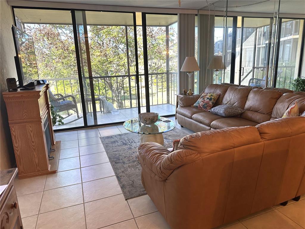 A living room features tile flooring, a leather sofa, a fireplace, and sliding glass doors — 618 BIRD BAY DRIVE S UNIT 201, VENICE, FL