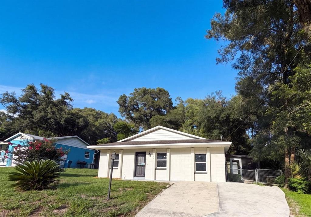 A single-story, light-colored concrete block house with a concrete driveway and surrounding trees — 2230 SPRING HOLLOW DRIVE, ORANGE CITY, FL