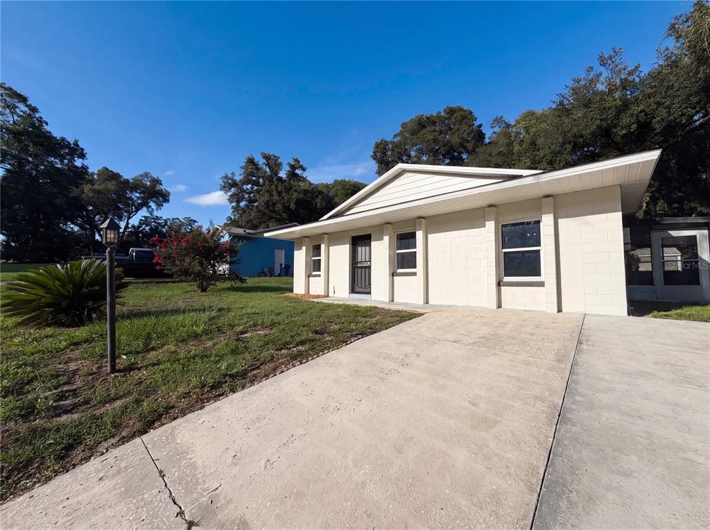 A single-story house with a concrete block exterior and a concrete driveway — 2230 SPRING HOLLOW DRIVE, ORANGE CITY, FL