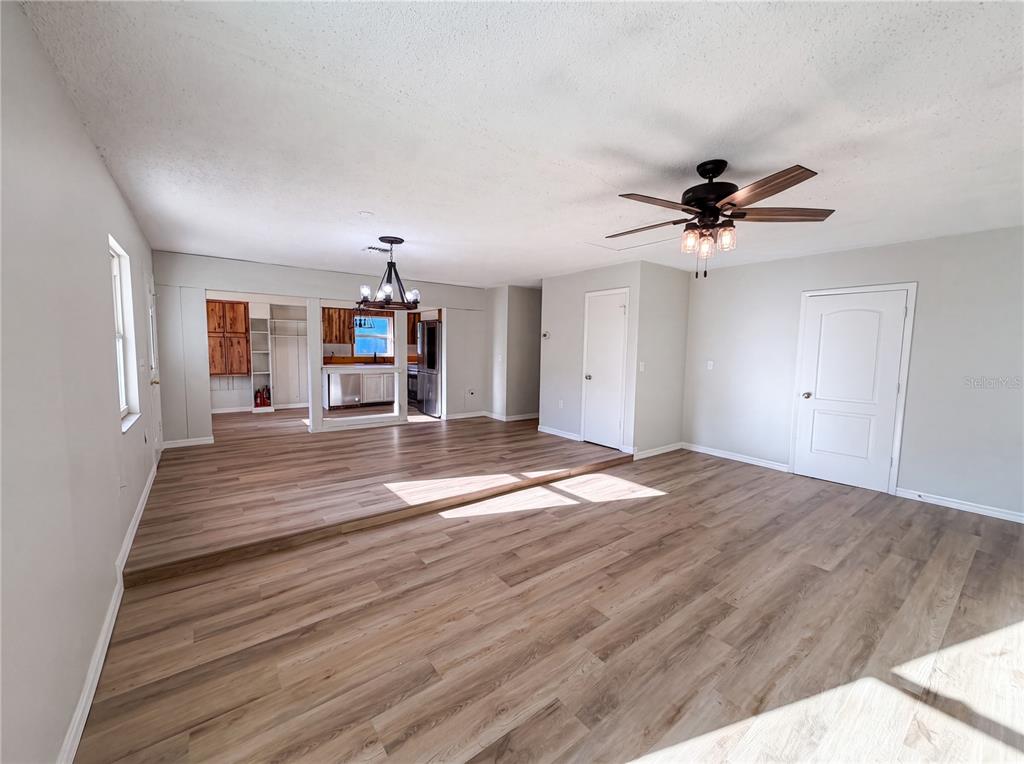 A living room with light wood-look flooring features a raised dining area and two doors — 2230 SPRING HOLLOW DRIVE, ORANGE CITY, FL