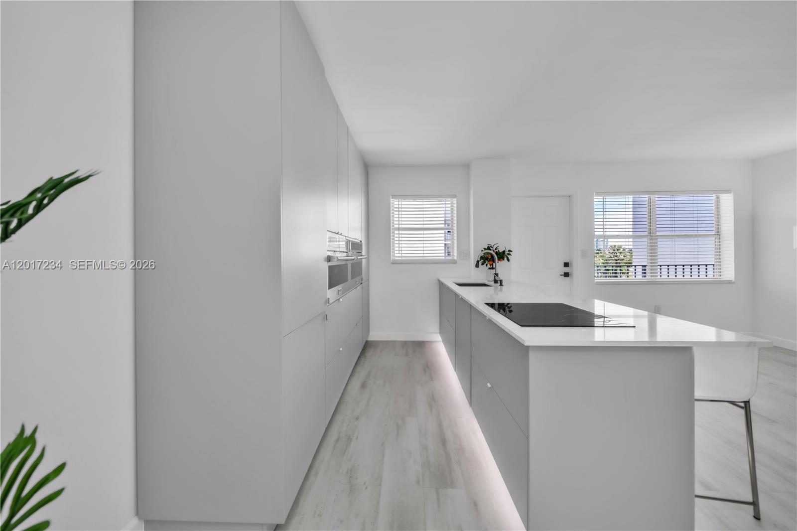 A modern kitchen features light gray cabinetry, a white island with a cooktop, and light flooring — 1720 Jefferson St # 511, Hollywood FL 33020, HOLLYWOOD, FL