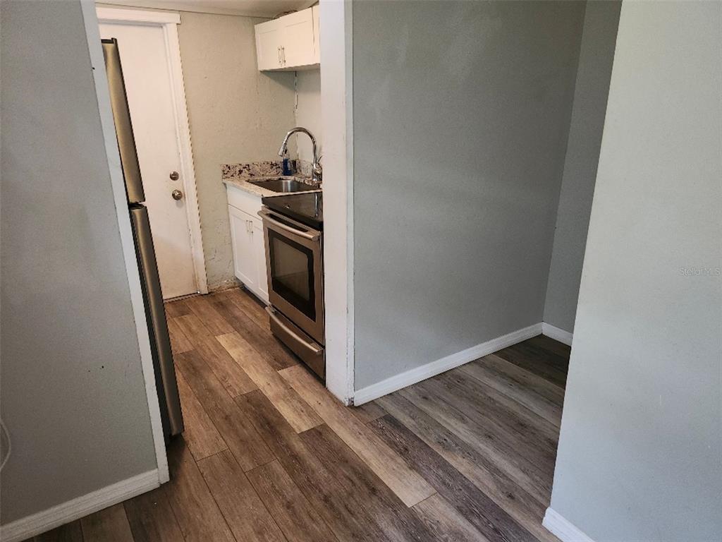 A small kitchen features stainless steel appliances, white cabinets, and wood-look flooring — 1426 10TH STREET W, BRADENTON, FL
