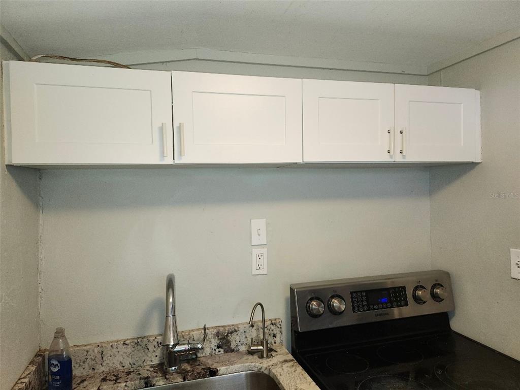 A kitchen area features white shaker cabinets, a granite countertop, and a stainless steel stove — 1426 10TH STREET W, BRADENTON, FL