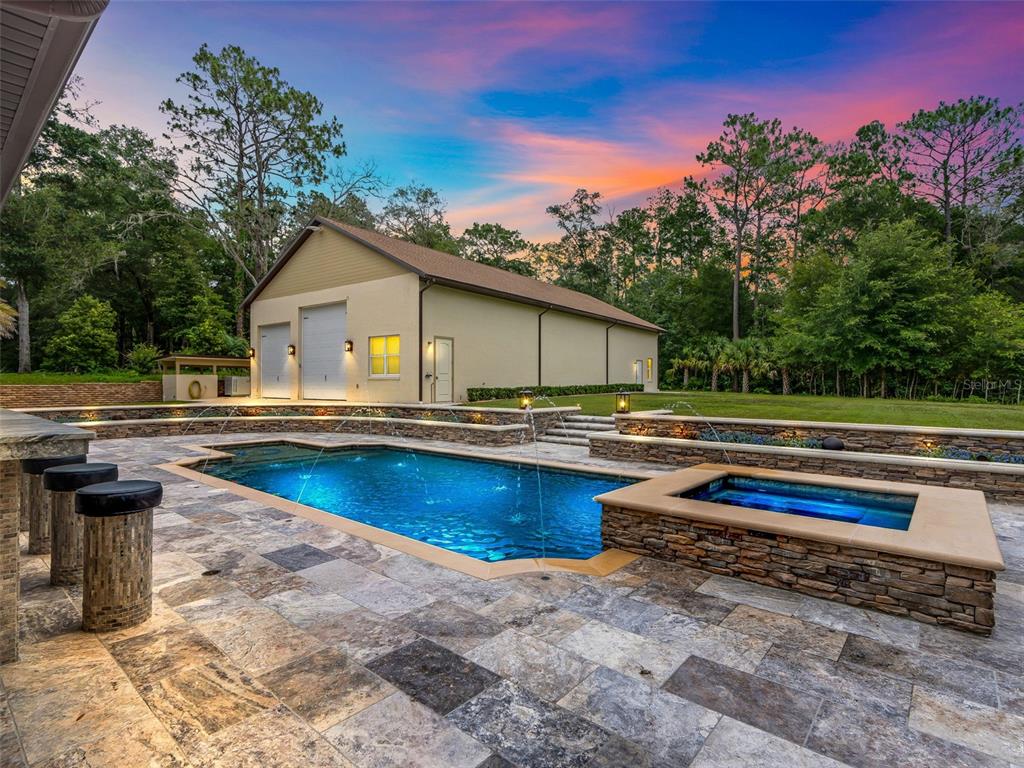 An outdoor patio features a swimming pool, a raised hot tub, and a detached garage — 10170 SW 202ND CIRCLE, DUNNELLON, FL