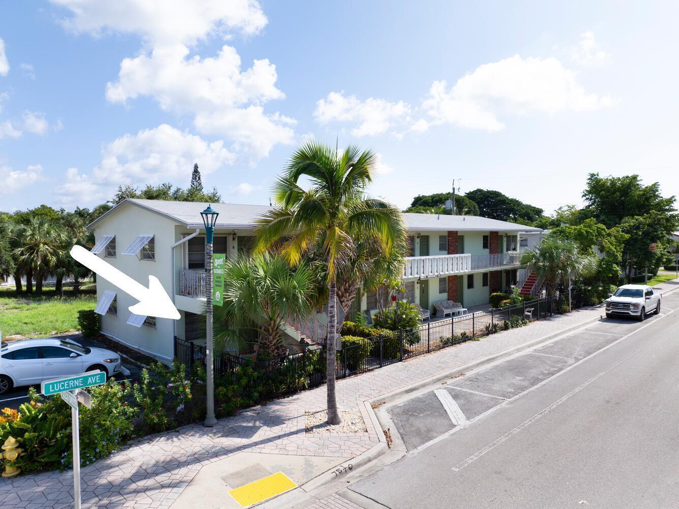 An exterior view of a two-story apartment building with a palm tree and street sign — 220 Lucerne Avenue # 1, FL 33460, FL