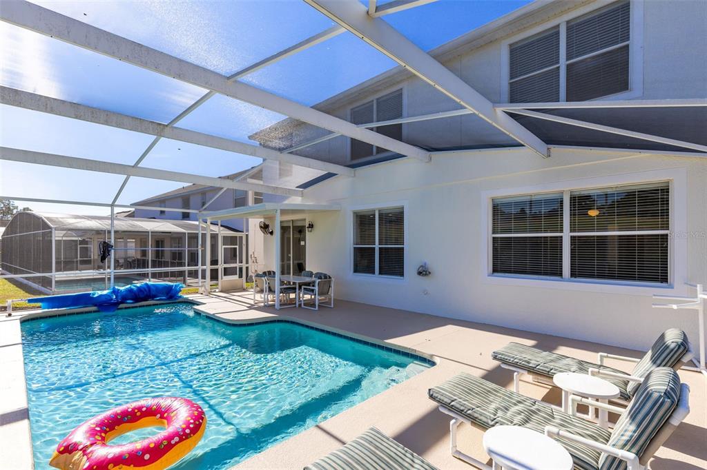 A screened-in patio features a swimming pool, lounge chairs, and a dining set — 142 BIRKDALE STREET, DAVENPORT, FL