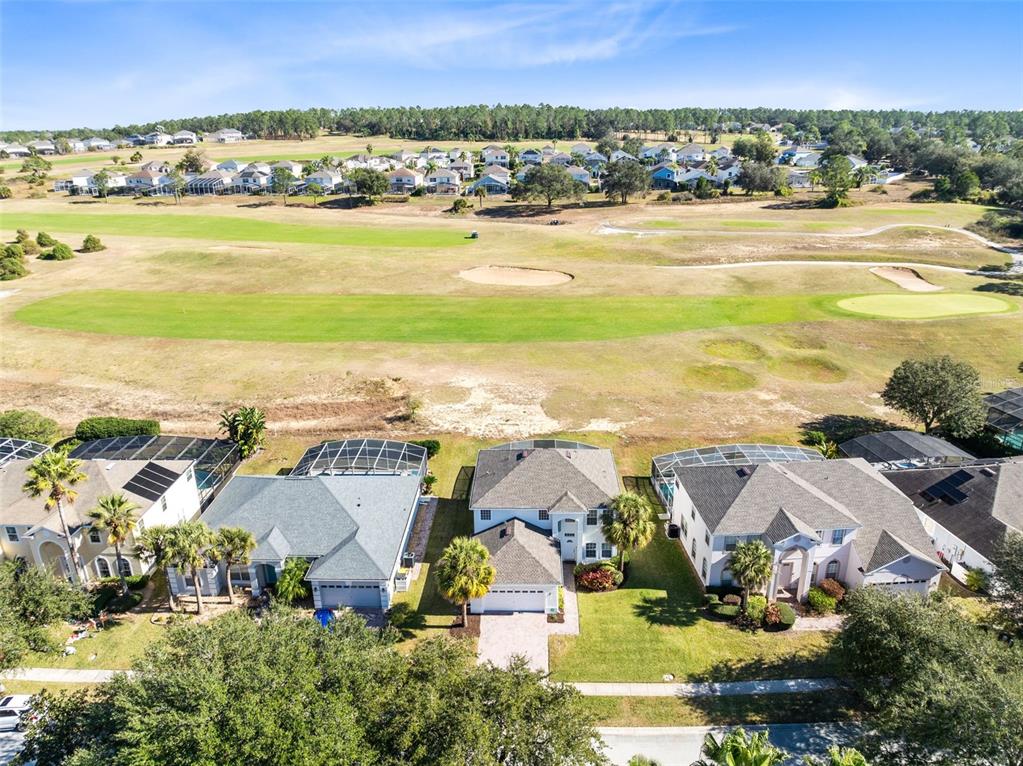 An aerial view shows three suburban houses with screened pools overlooking a golf course — 142 BIRKDALE STREET, DAVENPORT, FL