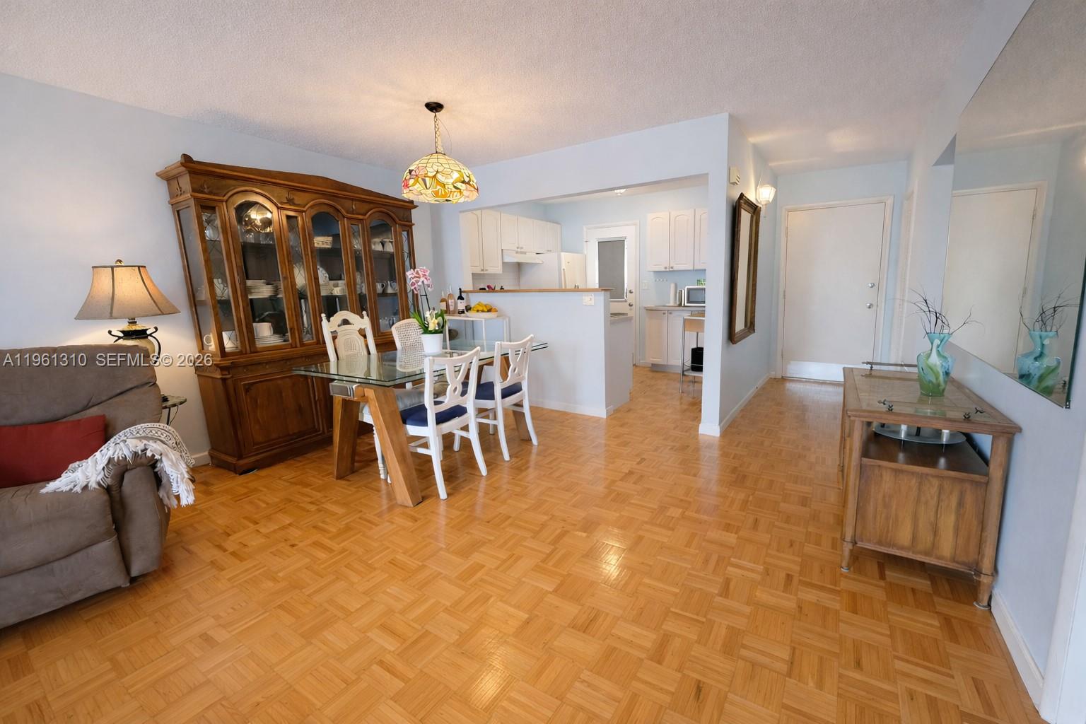 A dining area with a glass table and hutch opens into a kitchen with light cabinetry — 16750 NE 14th Ave # 202, Miami FL 33162, MIAMI, FL