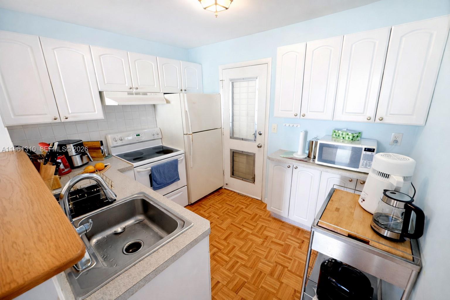 A kitchen features white cabinets, a white stove, a refrigerator, and light-colored countertops — 16750 NE 14th Ave # 202, Miami FL 33162, MIAMI, FL