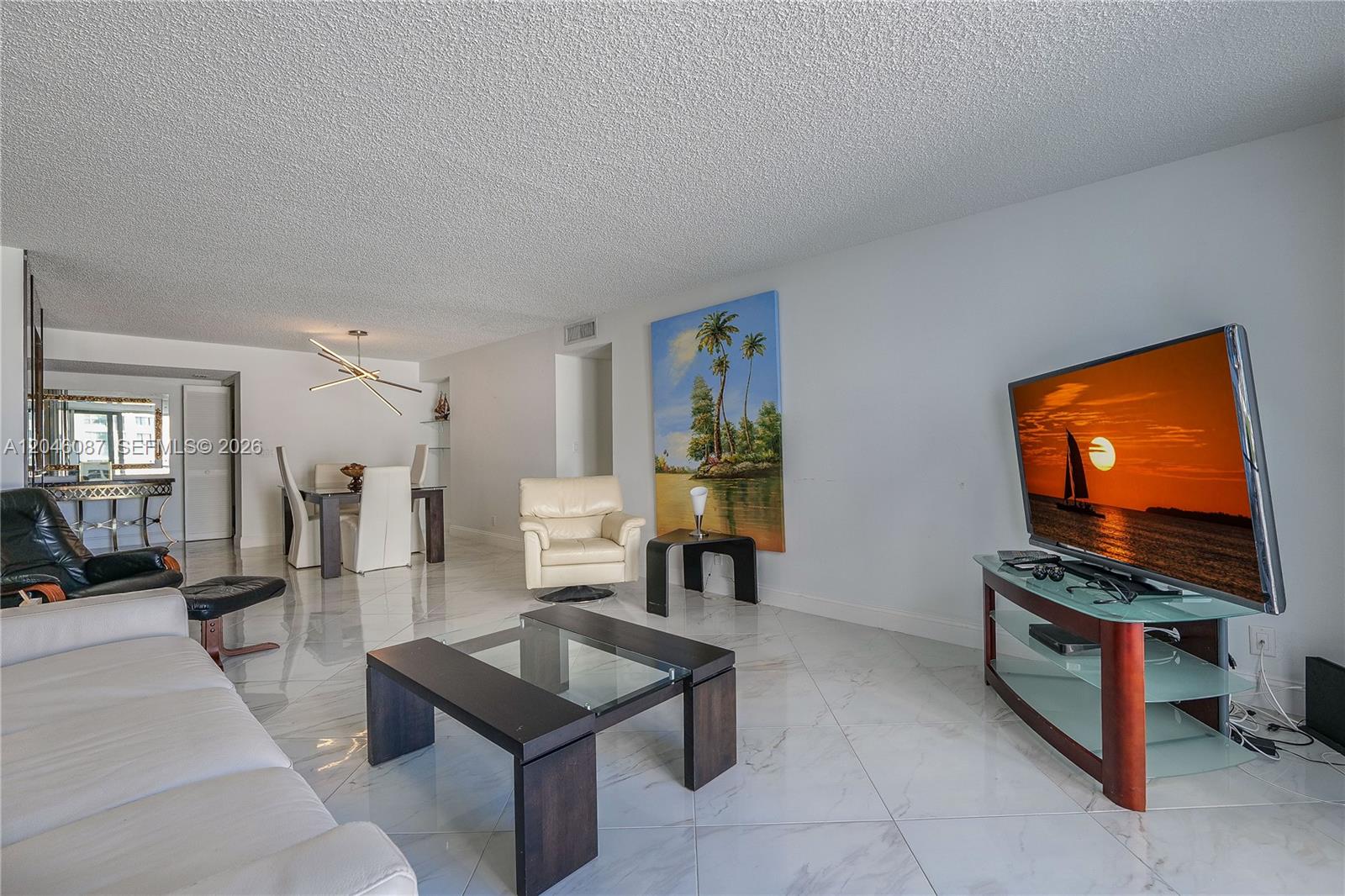 A living room with white marble floors, a glass coffee table, and a television — 2401 S Ocean Dr # 305, Hollywood FL 33019, HOLLYWOOD, FL