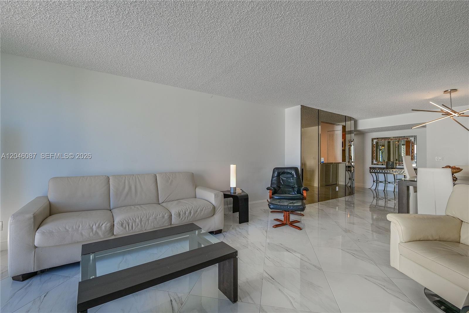 A living room features white marble floors, a beige sofa, and a black leather recliner — 2401 S Ocean Dr # 305, Hollywood FL 33019, HOLLYWOOD, FL