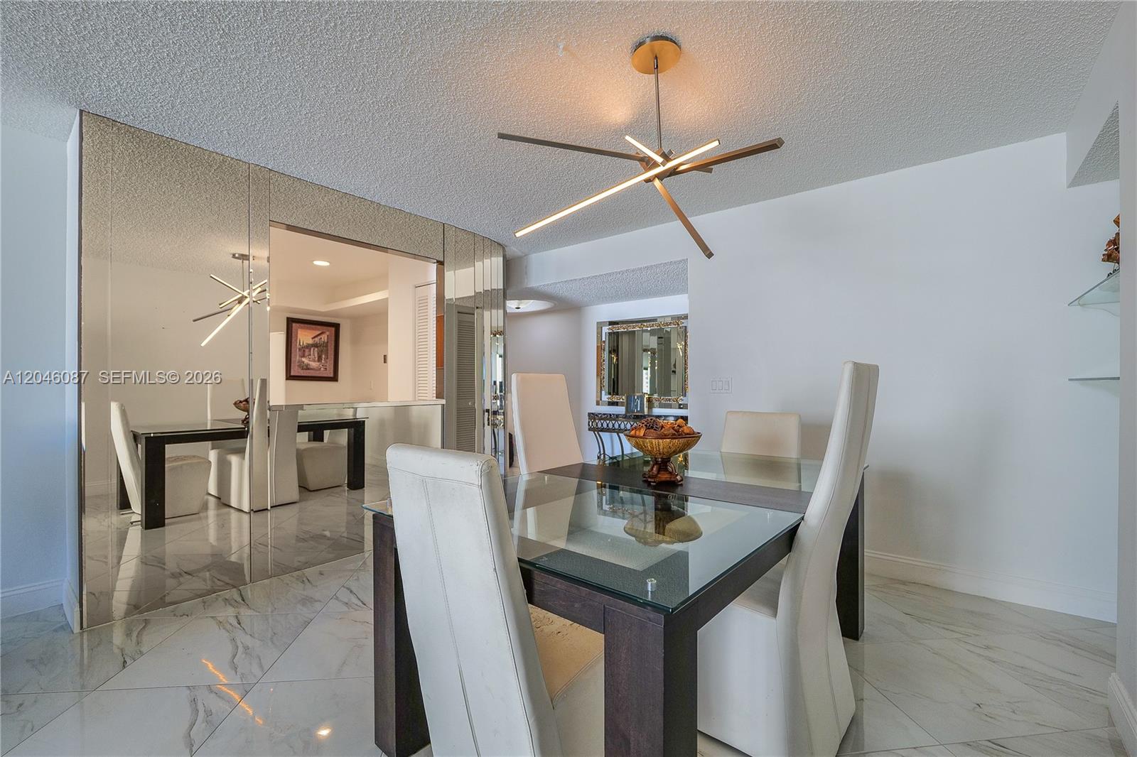 A dining room features a glass-topped table, white chairs, mirrored walls, and marble flooring — 2401 S Ocean Dr # 305, Hollywood FL 33019, HOLLYWOOD, FL