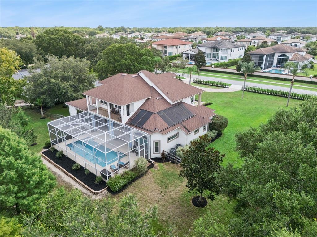 An aerial view shows a two-story house with a screened pool and solar roof panels — 4282 MCKINNON ROAD, WINDERMERE, FL