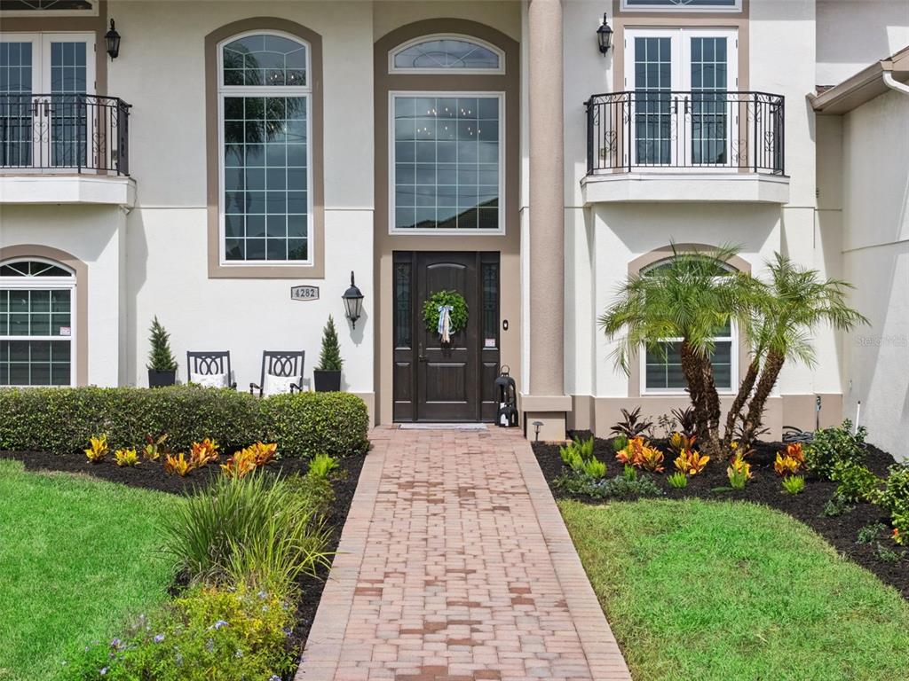 A brick walkway leads to the front entrance of a two-story home with balconies — 4282 MCKINNON ROAD, WINDERMERE, FL