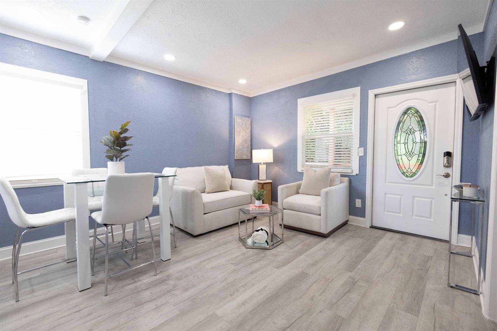 A living room with blue walls, light wood flooring, white furniture, and a glass-paneled front door — 420 Avenida Alegre # 4, West Palm Beach FL 33405, WEST PALM BEACH, FL