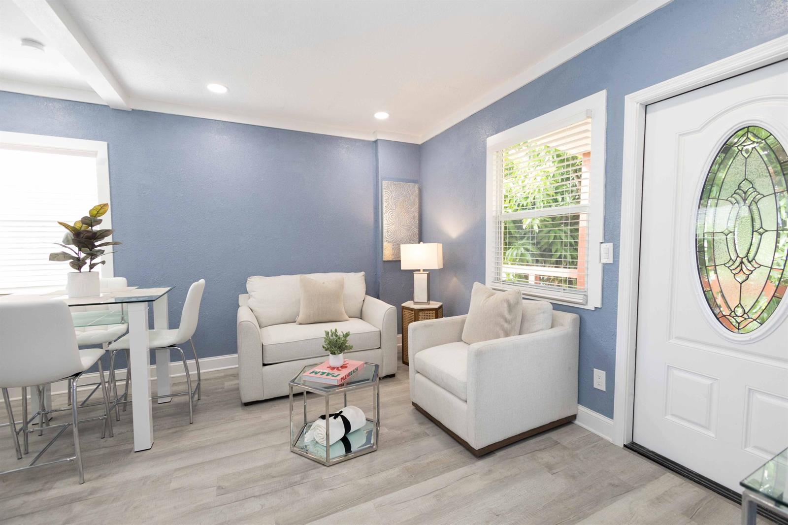 A living area with blue walls, white chairs, a glass coffee table, and a front door — 420 Avenida Alegre # 4, West Palm Beach FL 33405, WEST PALM BEACH, FL