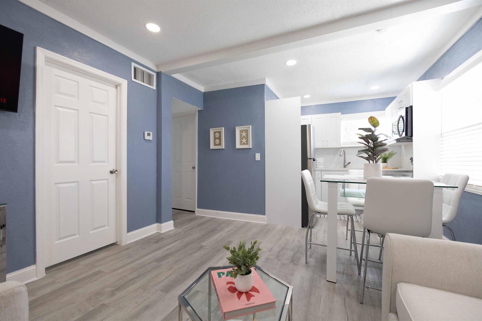 A living room with blue walls and light wood flooring flows into a white kitchen — 420 Avenida Alegre # 4, West Palm Beach FL 33405, WEST PALM BEACH, FL