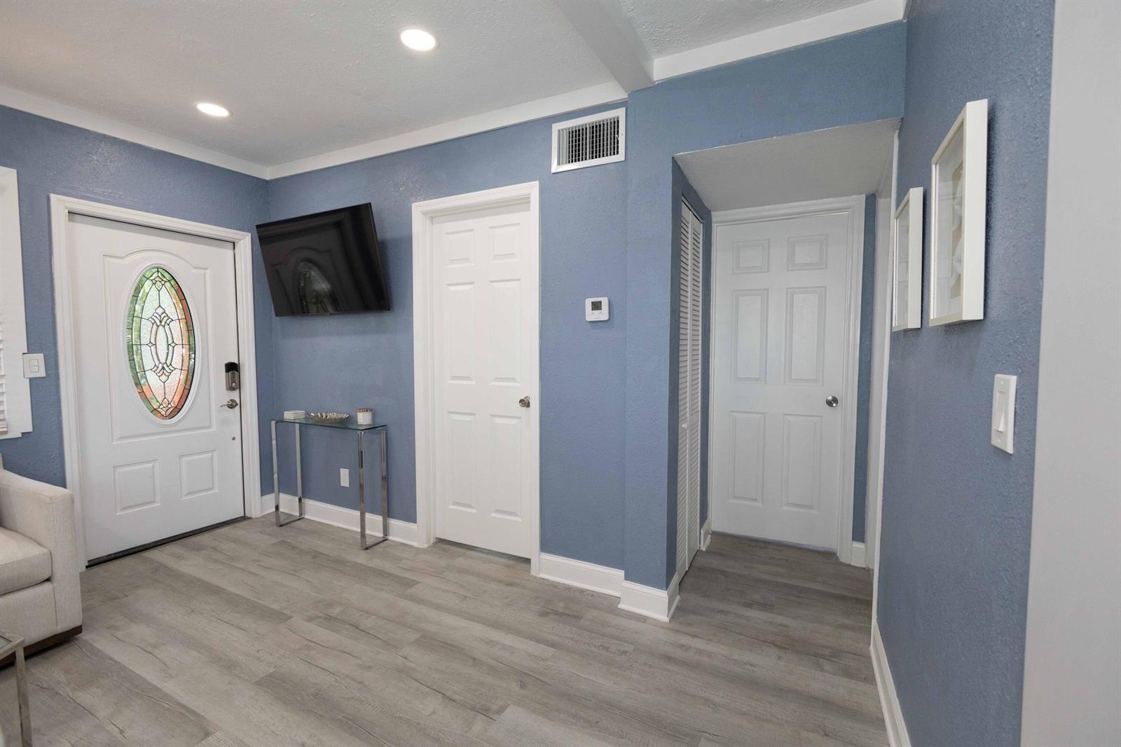 A blue-walled entryway features a white front door, two interior doors, and wood-look flooring — 420 Avenida Alegre # 4, West Palm Beach FL 33405, WEST PALM BEACH, FL