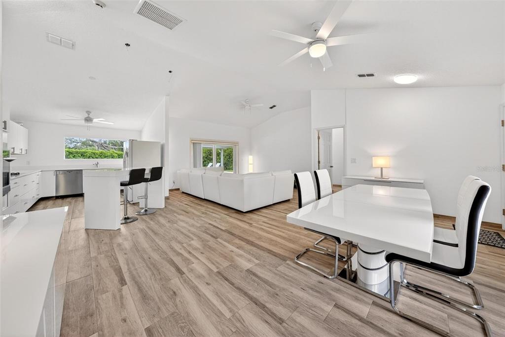 An open-concept living area features a white kitchen, dining space, and living room with wood-look flooring — 12623 LAKE DENISE BOULEVARD, CLERMONT, FL