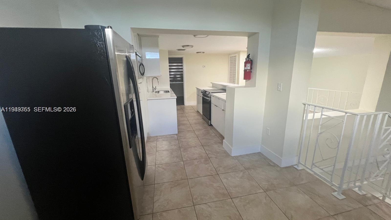 A kitchen with tile floors, white cabinets, stainless steel appliances, and a red fire extinguisher — 1251 Little River Dr, Miami FL 33147, MIAMI, FL