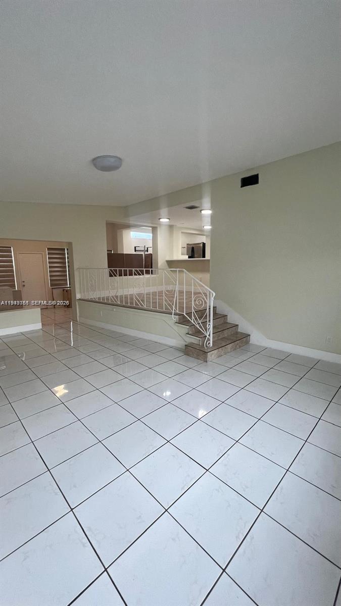 A room with white tiled floors features a raised platform area accessed by stairs — 1251 Little River Dr, Miami FL 33147, MIAMI, FL