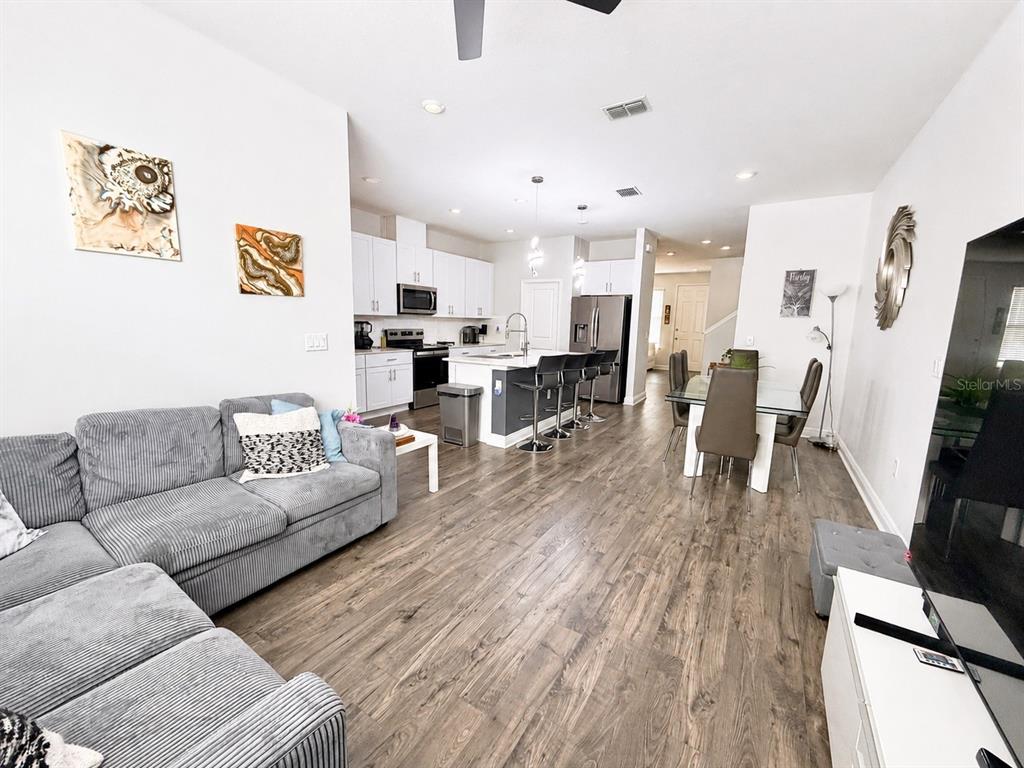An open-concept living room and kitchen featuring wood-look flooring and a central island — 16435 HAMLIN HILLS ROAD, WINTER GARDEN, FL