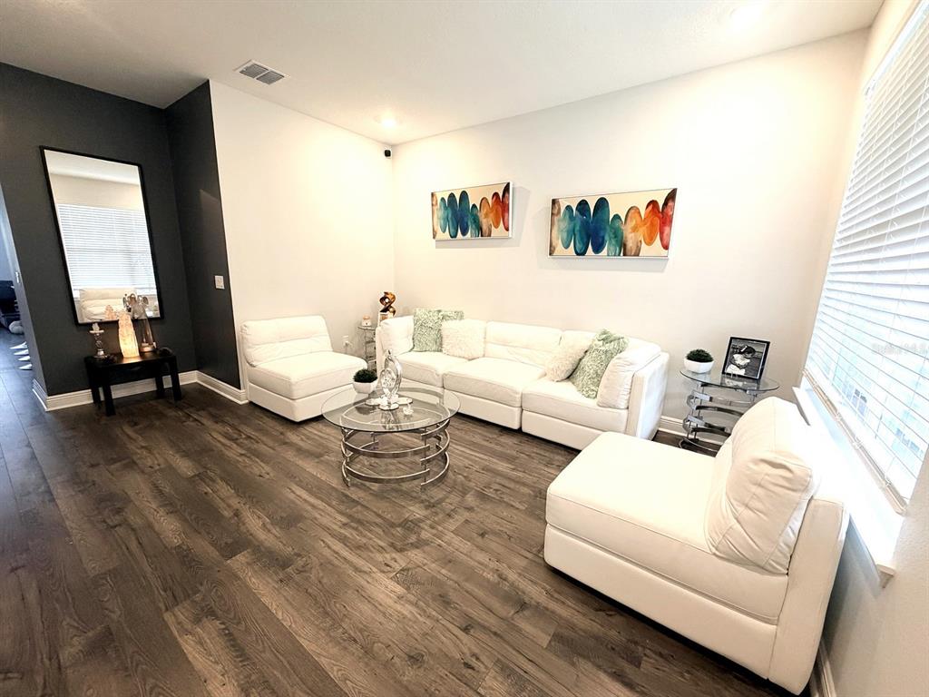 A living room features white modular seating, a glass coffee table, and dark wood flooring — 16435 HAMLIN HILLS ROAD, WINTER GARDEN, FL