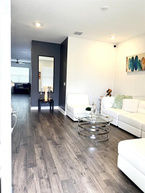 A living room features white sofas, a glass coffee table, and dark wood-look flooring — 16435 HAMLIN HILLS ROAD, WINTER GARDEN, FL