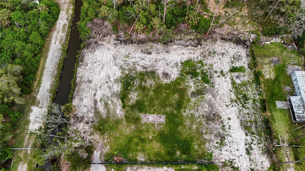 An aerial view of a cleared, sandy residential lot bordered by a canal and trees — 6644 OELSNER STREET, NEW PORT RICHEY, FL