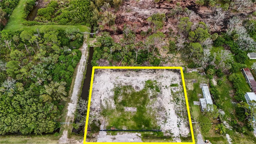 An aerial view shows a cleared, rectangular lot outlined in yellow next to a canal — 6644 OELSNER STREET, NEW PORT RICHEY, FL