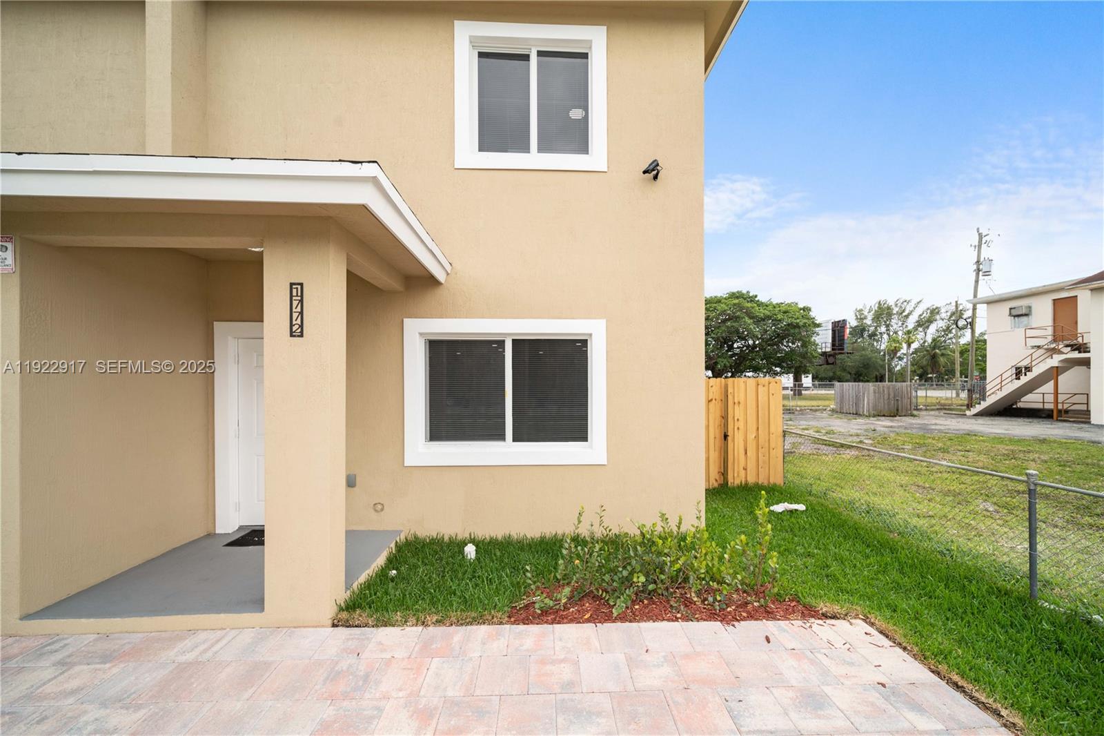 The exterior of a beige two-story building features a covered entryway and a paved patio — 1770 NW 55th St, Miami FL 33142, MIAMI, FL
