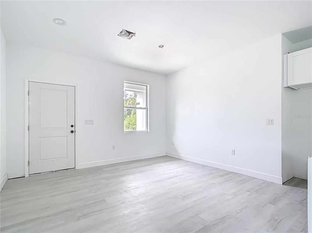 An empty room with white walls, light wood-look flooring, a window, and a white door — 16134 LIBOURN AVENUE, PORT CHARLOTTE, FL