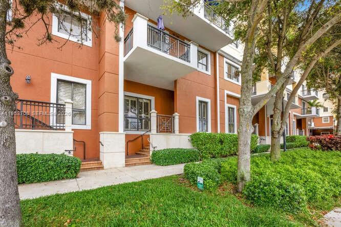 The exterior of a multi-story orange building features balconies, windows, and manicured hedges — 8395 SW 73rd Ave # 104, Miami FL 33143, MIAMI, FL