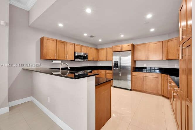 A kitchen features light wood cabinets, black countertops, stainless steel appliances, and tile flooring — 8395 SW 73rd Ave # 104, Miami FL 33143, MIAMI, FL