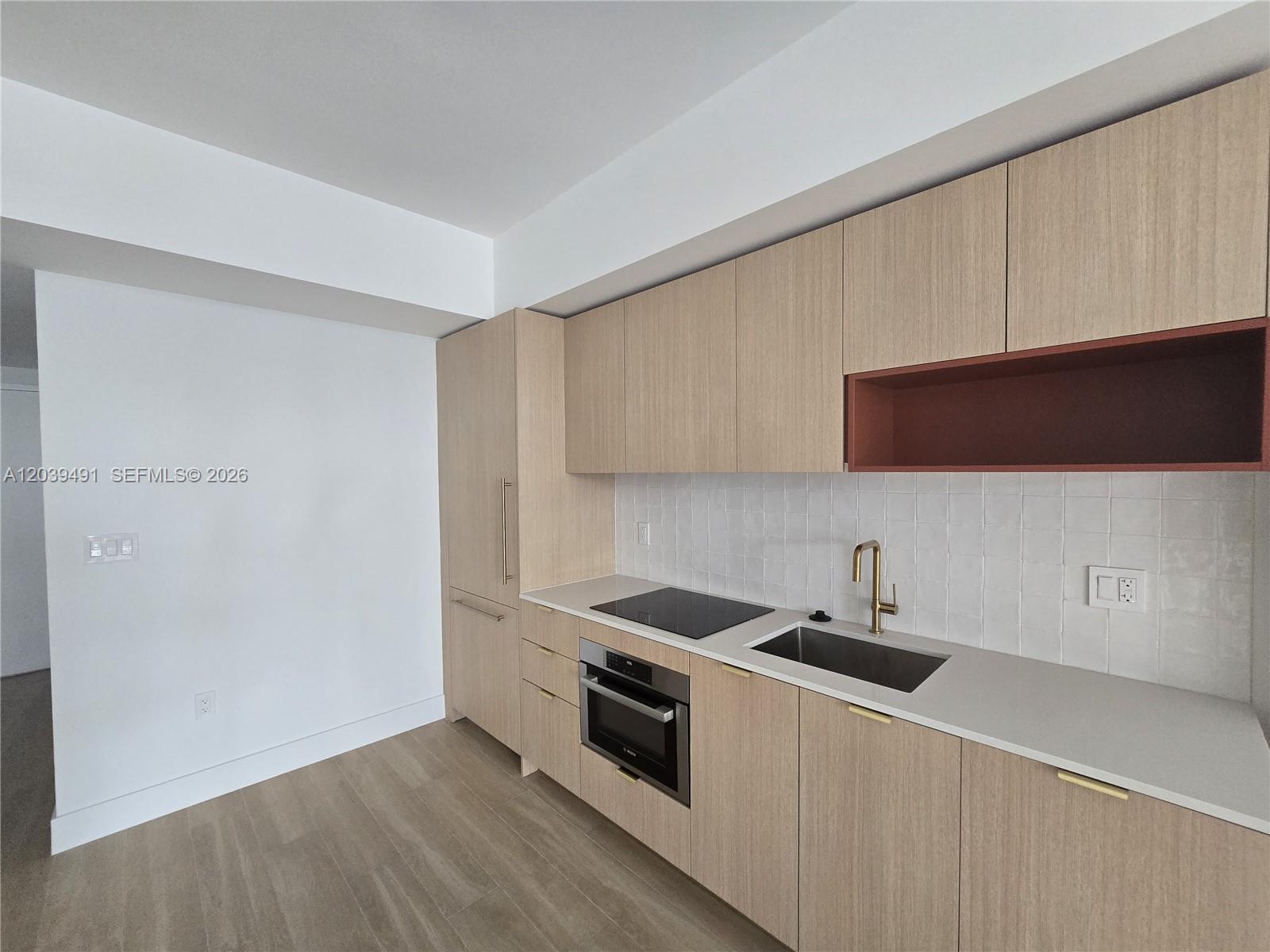 A modern kitchen features light wood cabinets, a white tiled backsplash, and stainless steel appliances — 90 NE 32ND ST # 305, Miami FL 33137, MIAMI, FL