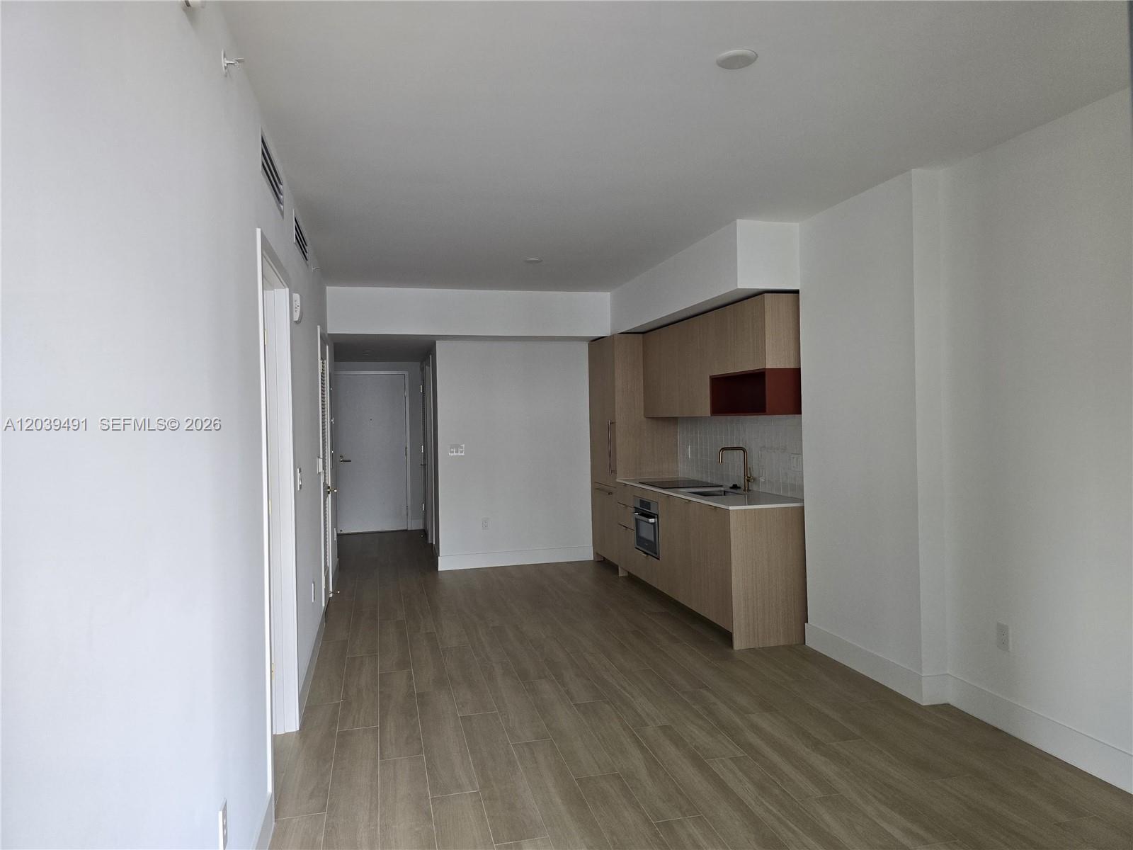 A modern kitchen with light wood cabinets and stainless steel appliances sits in an open-plan room — 90 NE 32ND ST # 305, Miami FL 33137, MIAMI, FL