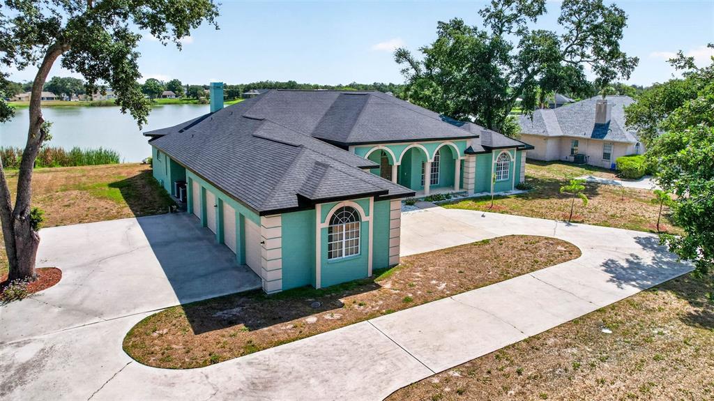 An aerial view shows a teal, single-story house with a dark roof and a circular driveway — 8911 RIVERLACHEN WAY, RIVERVIEW, FL