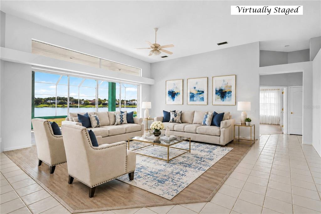 A living room with tile floors, a ceiling fan, and large windows overlooking a lake — 8911 RIVERLACHEN WAY, RIVERVIEW, FL