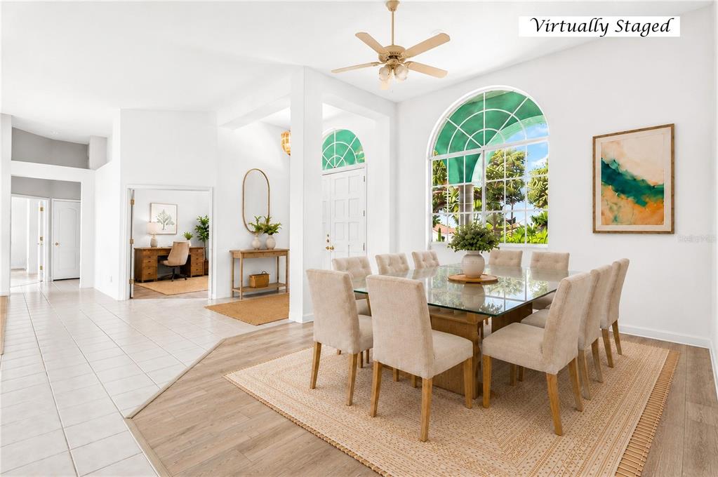 A dining room with a glass-top table, beige chairs, and a large arched window — 8911 RIVERLACHEN WAY, RIVERVIEW, FL