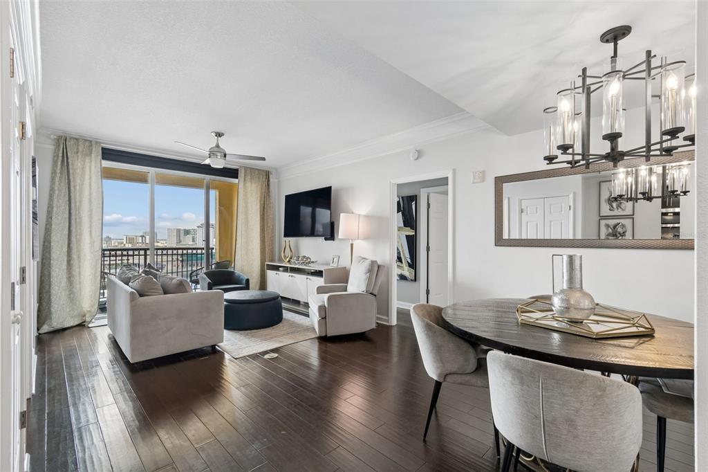 A living and dining area features dark hardwood floors, a balcony, and a modern chandelier — 345 BAYSHORE BOULEVARD UNIT 1510, TAMPA, FL