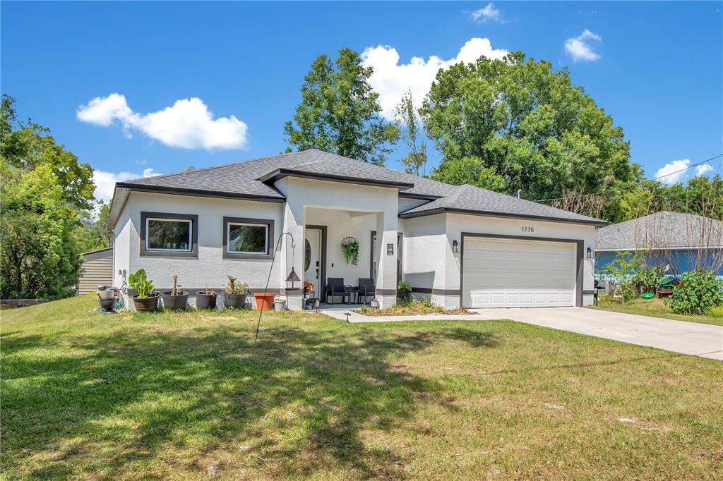 A single-story house with a white stucco exterior, a dark roof, and a two-car garage — 1775 19TH STREET, ORANGE CITY, FL