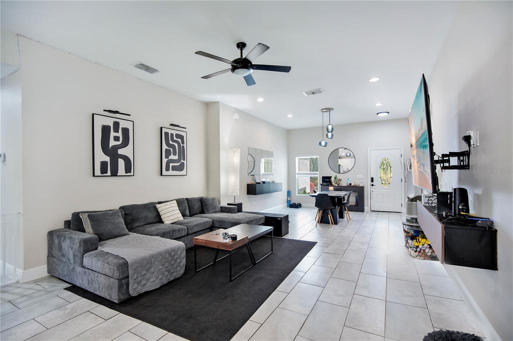 A living room features a grey sectional sofa, a black area rug, and a wall-mounted television — 1775 19TH STREET, ORANGE CITY, FL