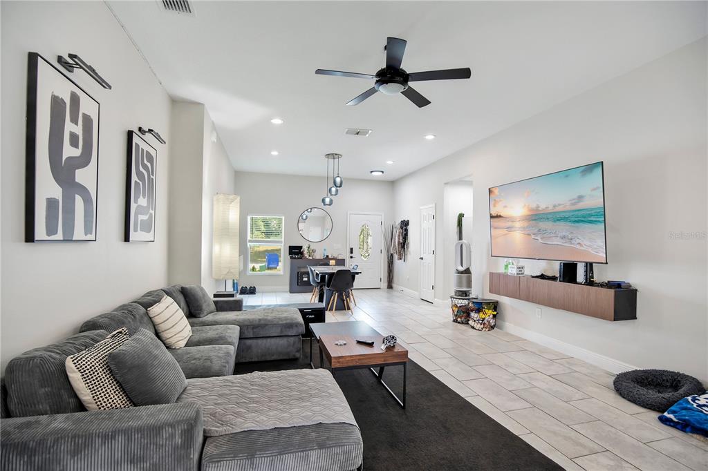 A living room features a grey sectional sofa, a wall-mounted television, and tile flooring — 1775 19TH STREET, ORANGE CITY, FL