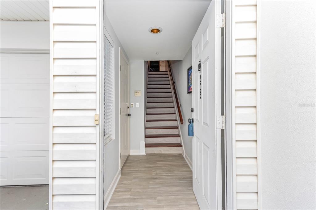 An entryway features light wood-look flooring, a white door, and a staircase leading upstairs — 320 ISLAND WAY UNIT 605, CLEARWATER BEACH, FL
