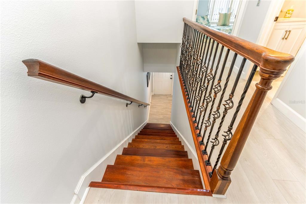 A wooden staircase with a decorative metal railing leads down to a lower level — 320 ISLAND WAY UNIT 605, CLEARWATER BEACH, FL