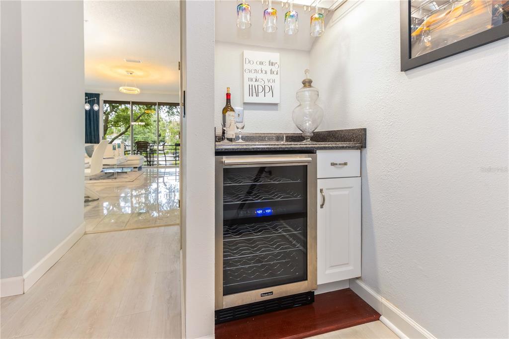 A wet bar features a wine cooler, white cabinetry, and a sign on the wall — 320 ISLAND WAY UNIT 605, CLEARWATER BEACH, FL