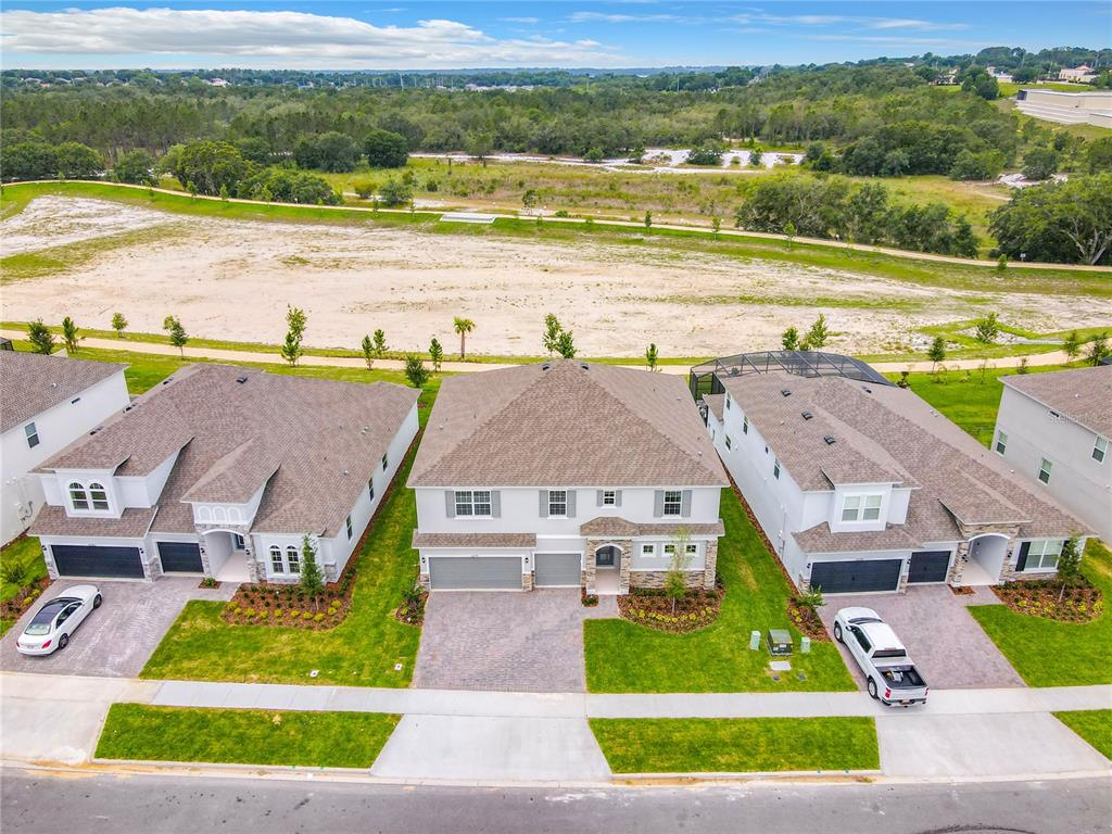 An aerial view shows three suburban houses with driveways facing a street and open land — 4379 RENLY LANE, CLERMONT, FL