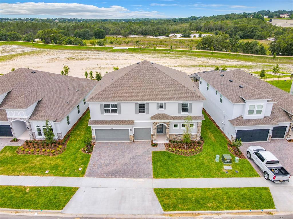 An aerial view shows three suburban houses with gray roofs and paved driveways — 4379 RENLY LANE, CLERMONT, FL