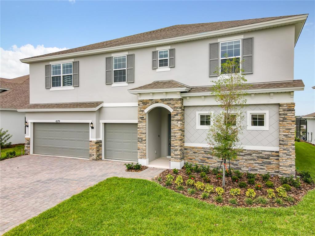 A two-story house features a stone-accented entryway, a paved driveway, and a two-car garage — 4379 RENLY LANE, CLERMONT, FL